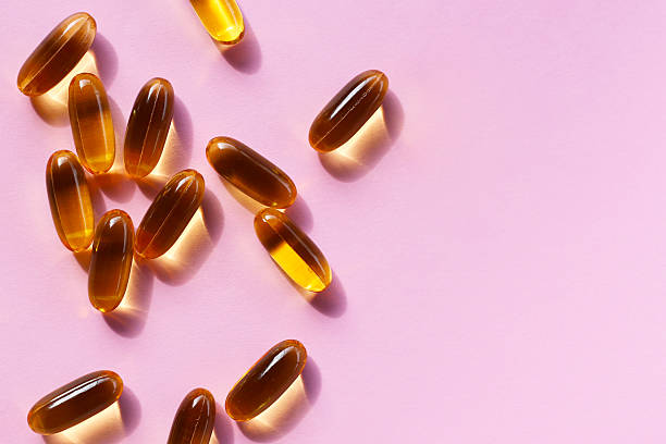 istock Golden fish oil capsules on pink background. 2228265516
