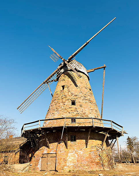 istock Dilapidated and abandoned medieval windmill, blue sky above 2228267499