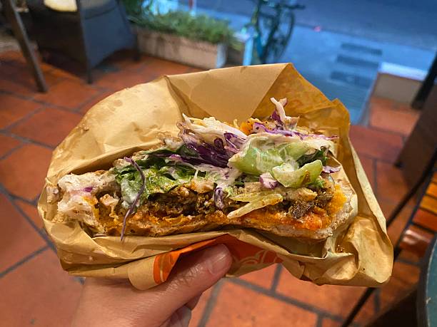 A freshly grilled kebab made with warm bread, tender chicken or beef, crisp vegetables, and a delicious blend of sauces (international food)