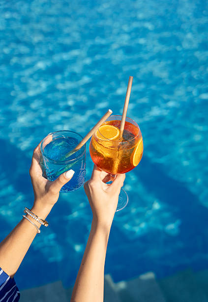 istock Two hands holding colorful cocktails above the pool 2228279606