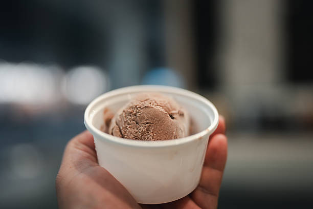 istock Hand holding white ice cream quart tub mockup containing chocolate ice cream scoops 2228284093