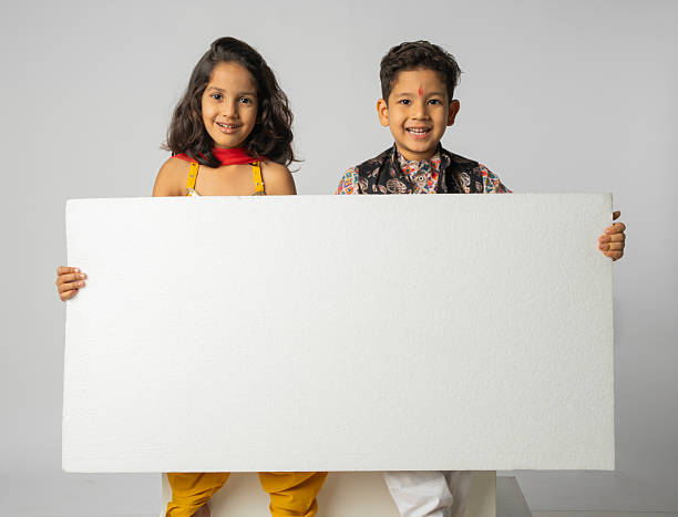 Happy kids in traditional clothing showing blank placard while enjoying Diwali festival against white background