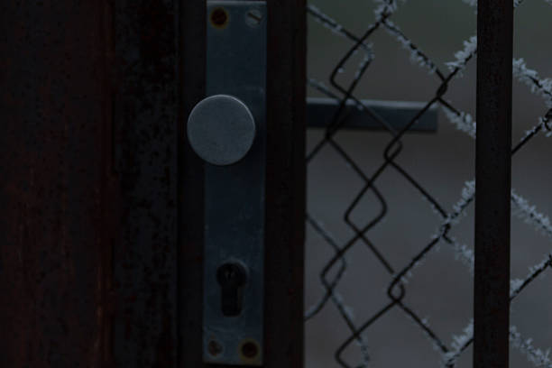 A chain link fence, securely positioned behind a door that features a keyhole, provides an added layer of security for any space