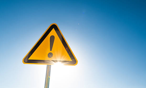 Warning sign with exclamation mark isolated on blue sky