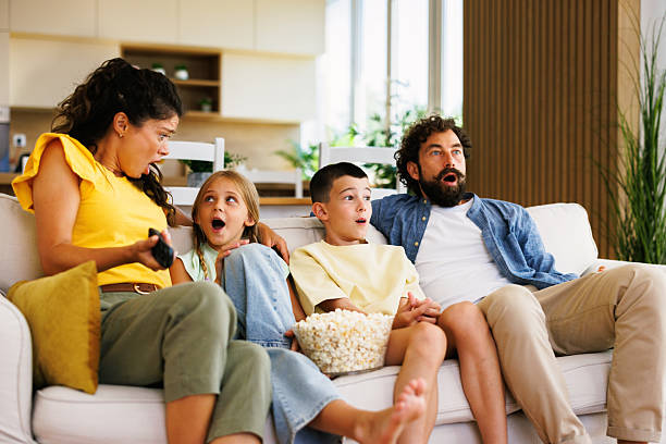 istock Family watching tv at home with surprised expression while eating popcorn 2228290262
