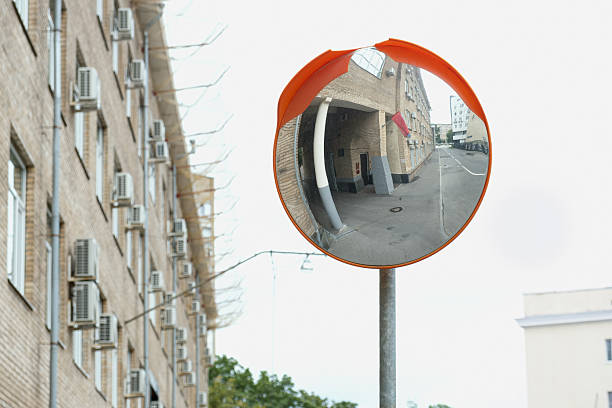 Street view with a convex safety mirror reflecting a narrow urban alley and brick building, symbolizing city surveillance, navigation, and visual distortion