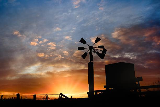 istock Sunrise Silhouette Wind Water Pump And Tank 2228292791