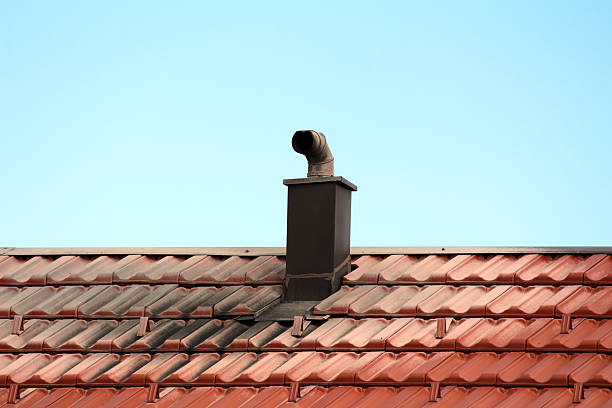 istock Rooftop metal chimney pipe on red clay tile roof under clear sky 2228302118