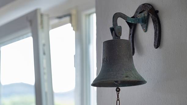 istock Old metal bell on white wall 2228302206