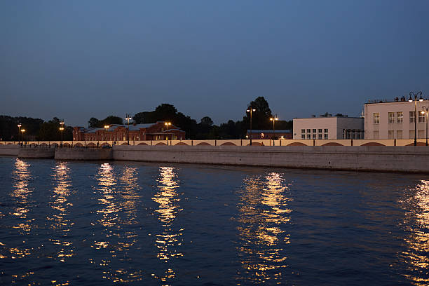 On a tranquil evening, the view of a beautiful waterfront showcases stunning city lights reflecting off the calm waters