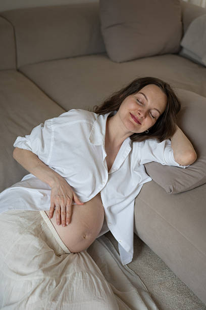 istock Pregnant woman relaxing on sofa, touching her belly 2228303009
