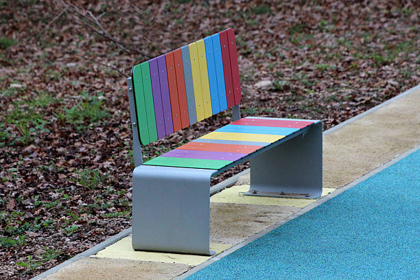 istock Vibrant multicolored park bench beside blue rubber pathway in forested play area 2228303152