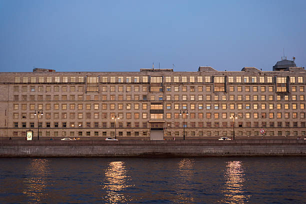 Experience a captivating view of a grand historic building illuminated by the evening dusk, reflected in calm water