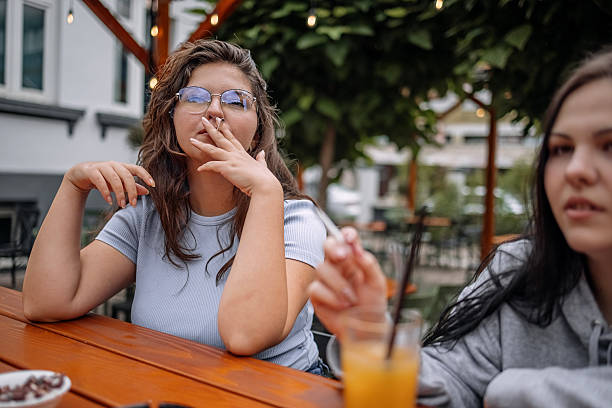 istock Group of friends having drink together at sidewalk cafe while enjoying talking and having a smoke 2228304780