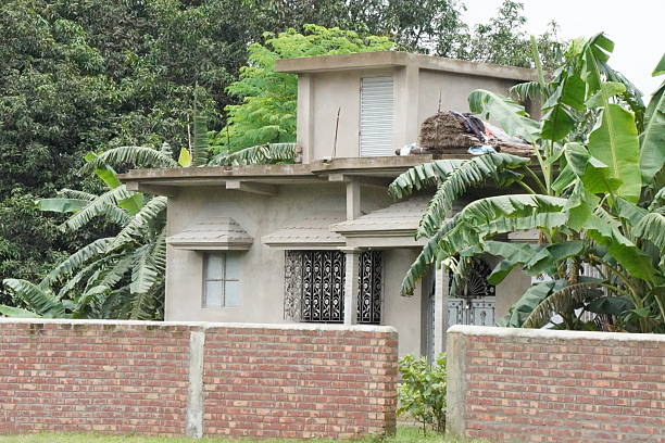A newly constructed building is surrounded with a wall, several banana trees inside the area