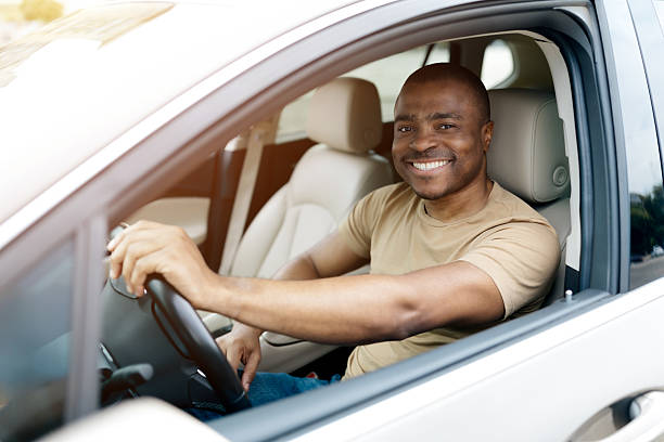 istock Confident black man smiling from window, sitting in driver seat in car 2228306971