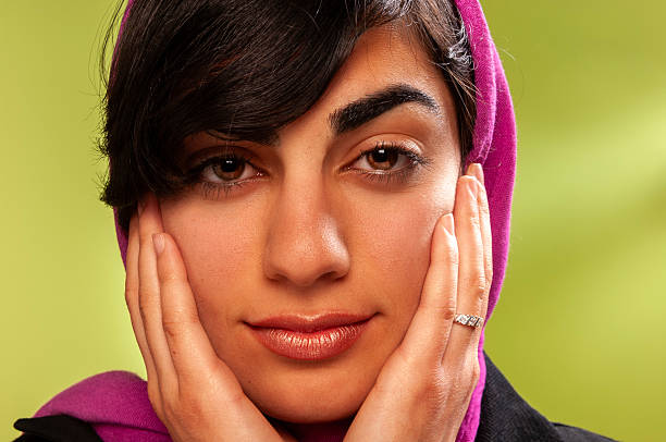 young Iranian woman with a colourful  simple headscarf (hijab or rousari), studio shot.