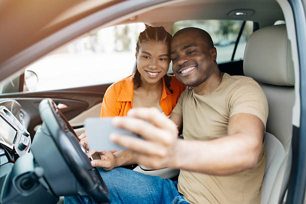 istock Smiling black couple taking a selfie inside their car, capturing fun travel 2228309096