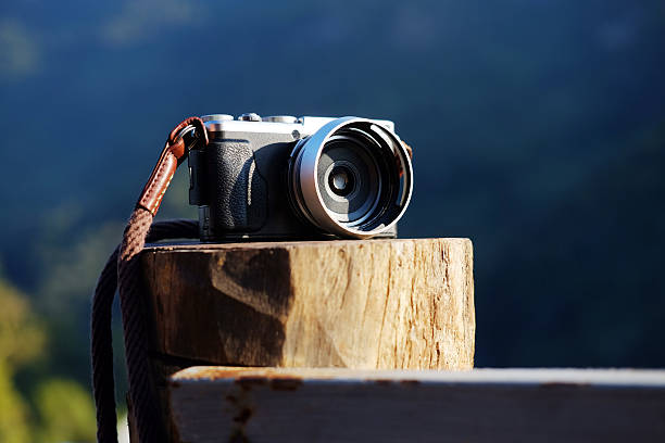 A vintage black and silver mirrorless camera on tree stump of terrace with mountain view in Chiangmai of Thailand