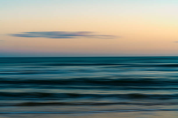 istock Calm ocean waves gently reaching the sandy shore under a soft pastel sky. Abstract 2228312654
