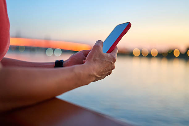 istock Woman using smartphone near river at sunset 2228312790
