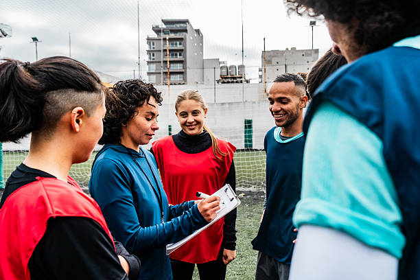 Female coach drawing tactics on clipboard for mixed soccer team