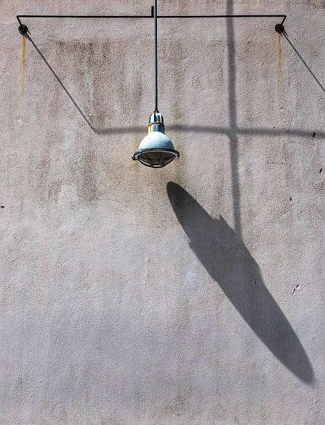 istock Industrial Light Fixture Casting Shadows on Weathered Concrete Wall 2228316156