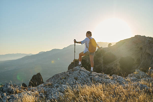istock Hiker Standing on a Rocky Cliff Overlooking Scenic Mountain Valley at Sunrise 2228316938
