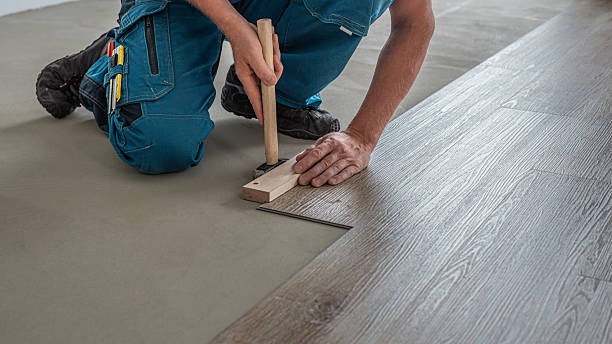 istock Floating floor work. The worker taps the board of vinyl plank to lock the click system. He is using hammer and wooden plank. 2228319231