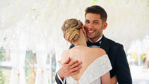 A newlywed young bride and broom are hugging and kissing each other before their wedding ceremony.