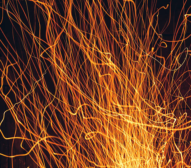 Yellow fire sparks is flying. Beautiful abstract background. Christmas evening at the fireplace. Art trail of firework. Burning trace glowing over black background. Natural pattern with copy space.