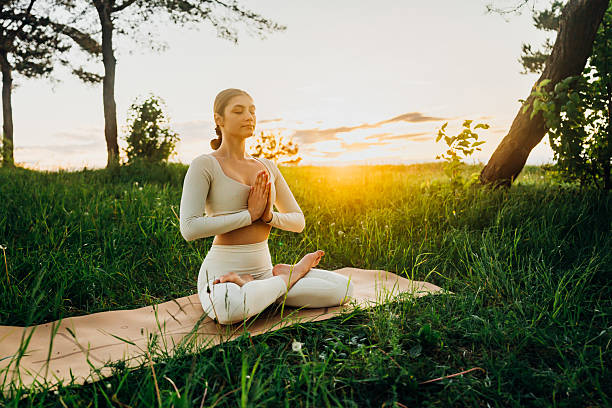 istock Young woman meditates in meadow at sunrise 2228326607