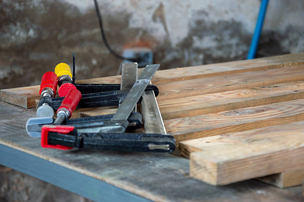 istock Various clamps and a wooden pallet lie on a workbench in a workshop, indicating preparation for a woodworking project 2228327890