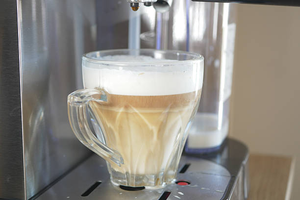 A latte being prepared in a sleek coffee machine at home.