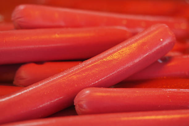 Bright red hot dogs stacked in a casual food setting