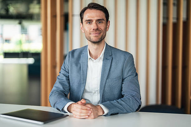 istock Thoughtful business man sitting on a desk and smiling 2228335289