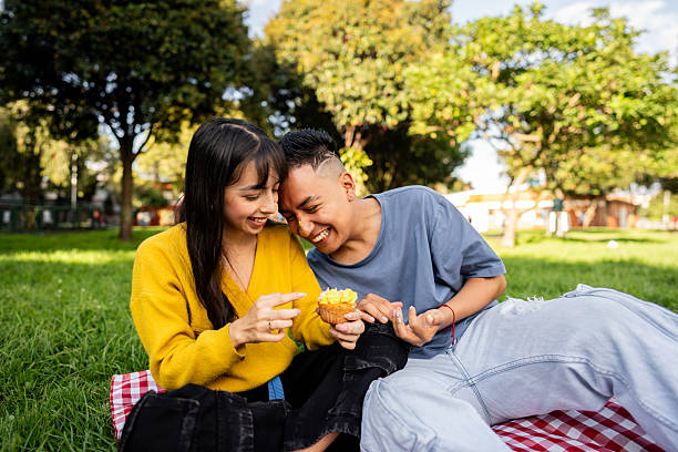 istock Young couple eating dessert during picnic on public park 2228337622