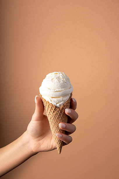 istock White ice cream scoop with ice cream cone in hand on bright background. Minimal summer concept. 2228339633