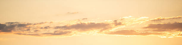 Golden hour light illuminates the sky as soft clouds reflect warm hues during sunset. The peaceful landscape creates a serene atmosphere