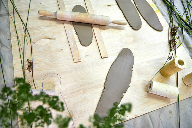 Rolled clay sheets laid out on a wooden surface with a rolling pin and cutting tools. A hands-on stage in crafting handmade clay napkin rings, where texture and shape begin to take form
