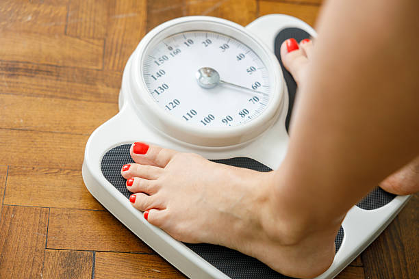 istock Woman checking weight on scale at home 2228353567