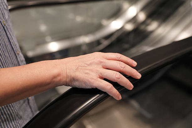 istock Senior Woman’s Hand Resting On Escalator Handrail 2228358493