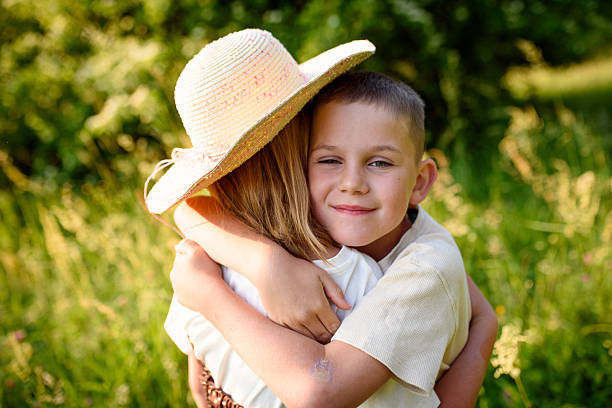 Siblings standing in tall grass during sunset. End of summer break concept.