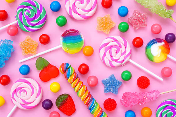 Colorful assortment of candies. Top down view flay lay over a pink background.