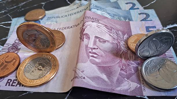 istock Coins on top of Brazilian real notes 2228361788