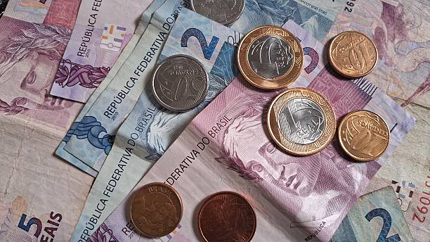 istock Coins on top of Brazilian real notes 2228361809