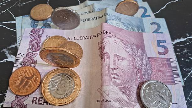 istock Coins on top of Brazilian real notes 2228361813