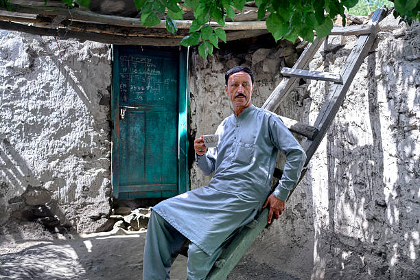 Senior from Pakistan farmer enjoying a cup of tea outside his traditional home