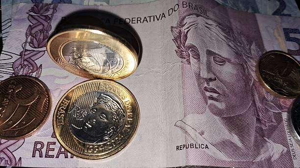 istock Coins on top of Brazilian real notes 2228362054
