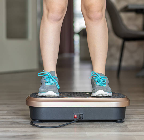 istock Individual standing on a vibration plate exercise machine in a modern home interior, showcasing fitness equipment and promoting active lifestyle and wellness 2228367823